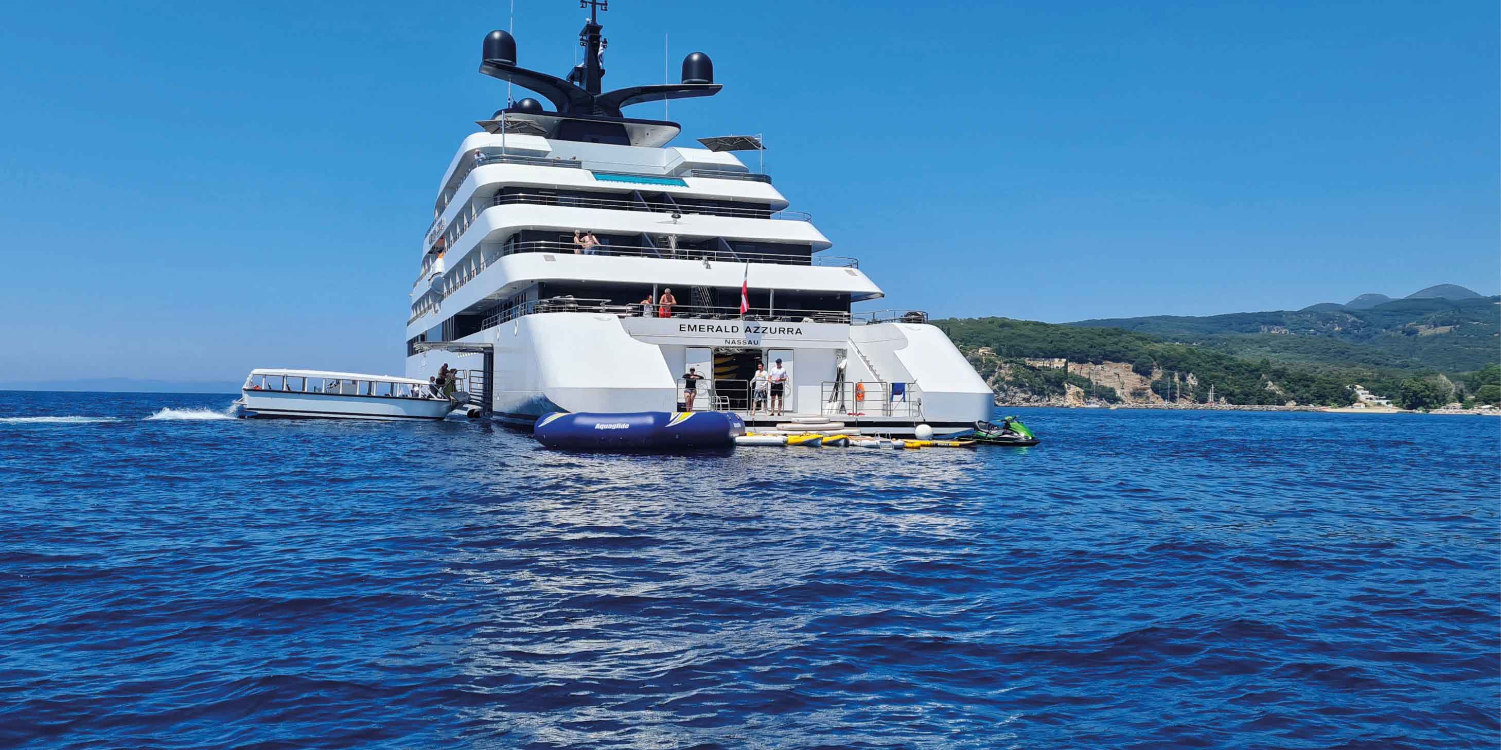 Luxury yacht on the deep blue sea, with guests gathering round the marina toys found near the rear of the yacht. 