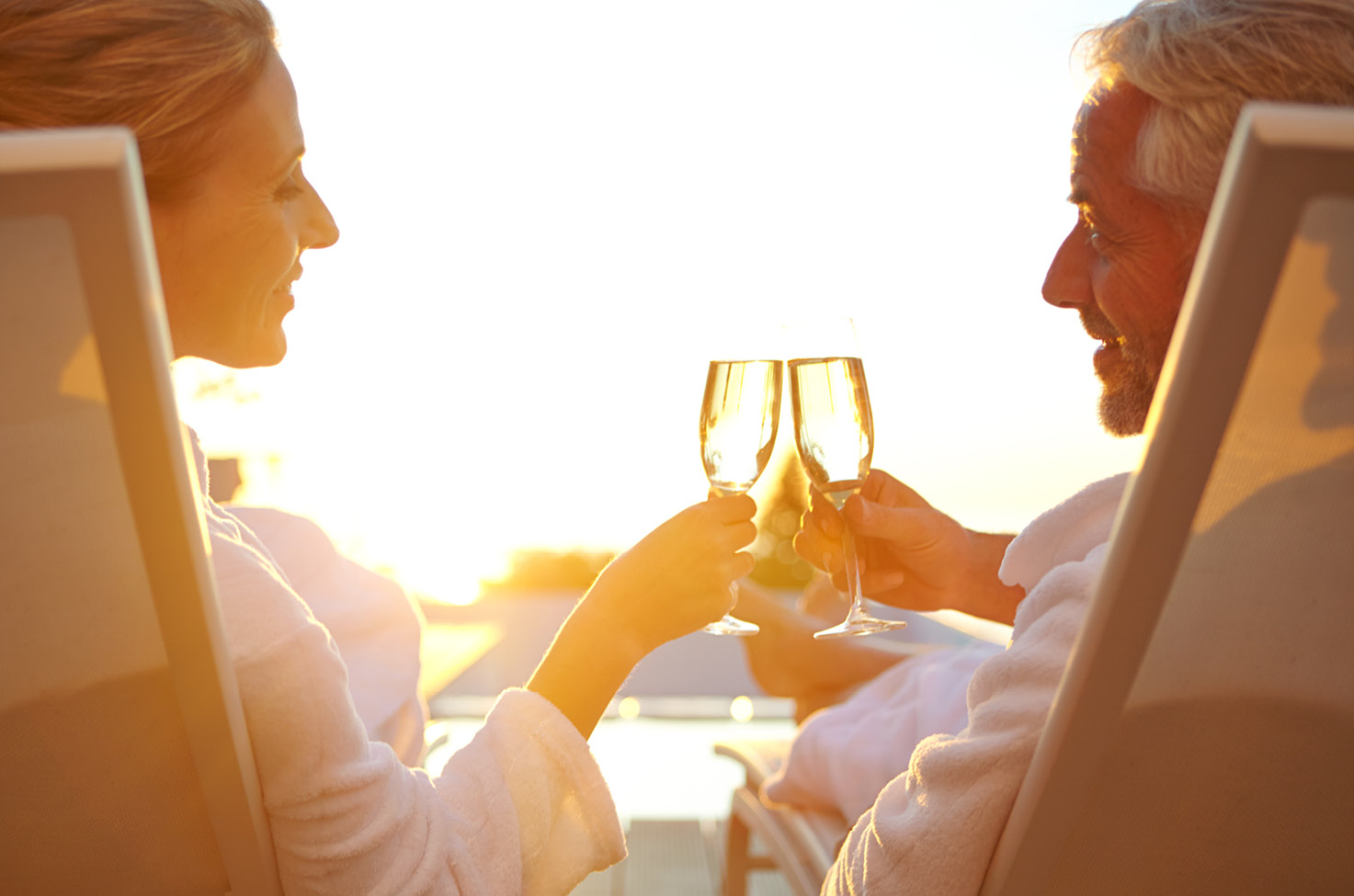 A man and woman sitting down cheersing with champagne