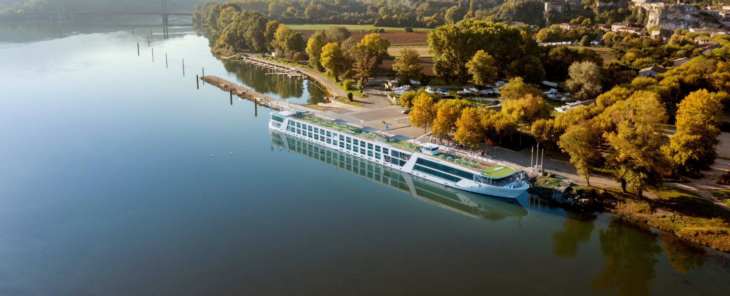 A luxurious river cruise boat is elegantly docked along the serene waters of the river Rhône, inviting travellers to embark.