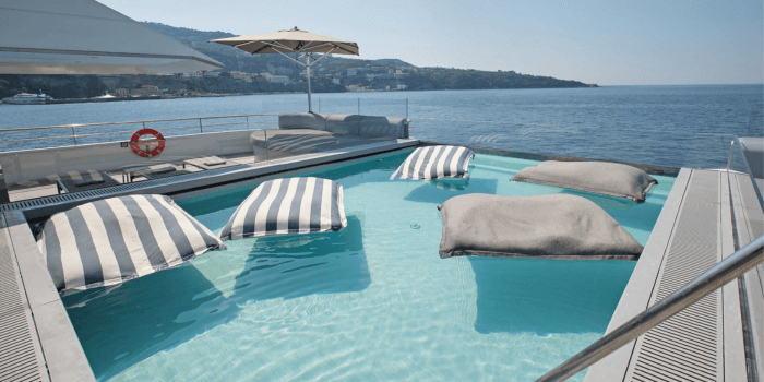 Man swimming in a large infinity-style swimming pool on board a luxury yacht, with stunning views of the sea