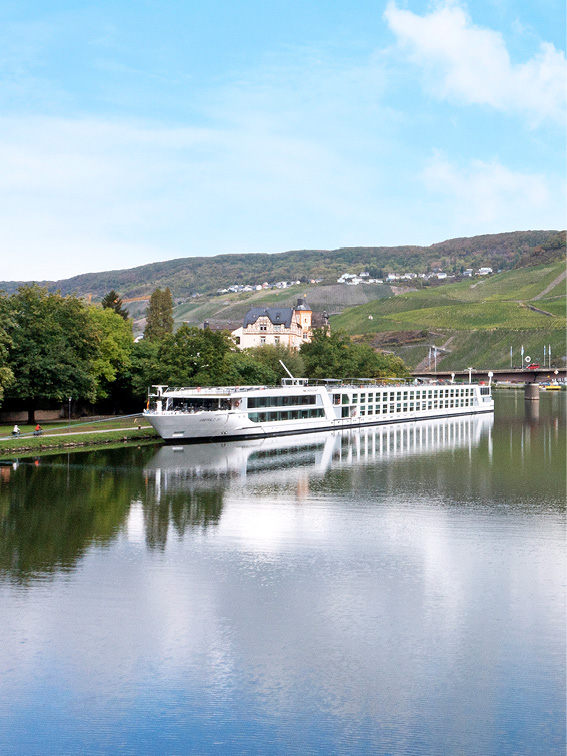 Luxury river ship docked in Bernkastel, Germany, with the landscape reflected in the water’s surface.