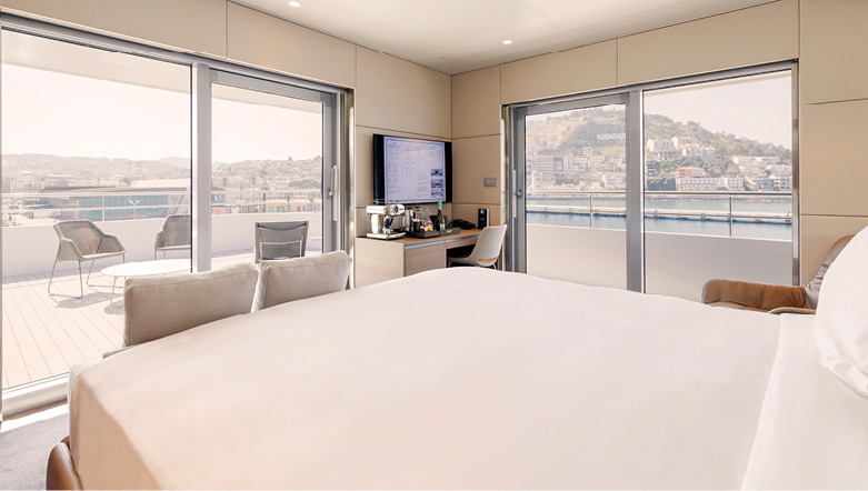 A large cabin on an Emerald Cruises yacht with comfortable bed facing an incredible view out across the terrace and balcony